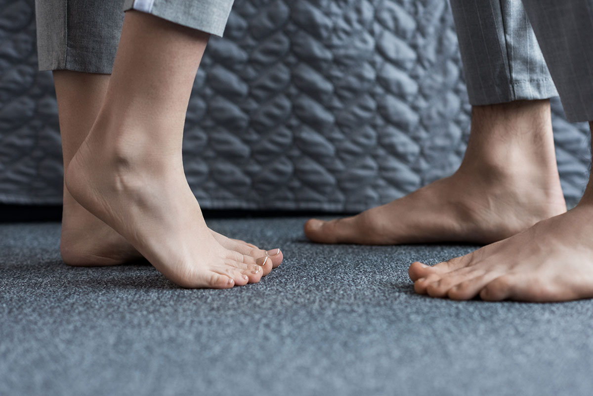 Cropped Image Of Boyfriend And Girlfriend Standing Barefoot On F