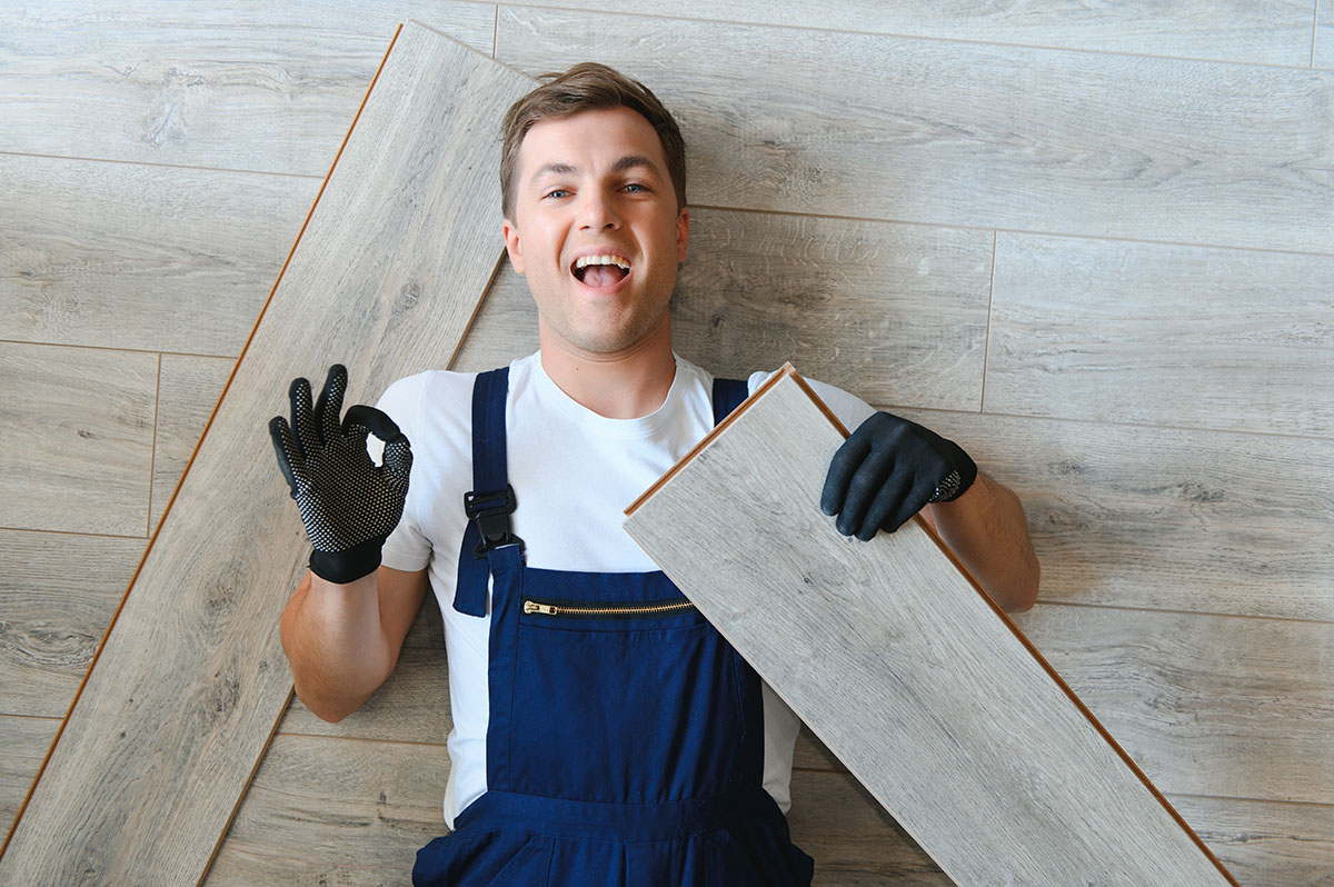 Man Laying Laminate Flooring In Construction Concept